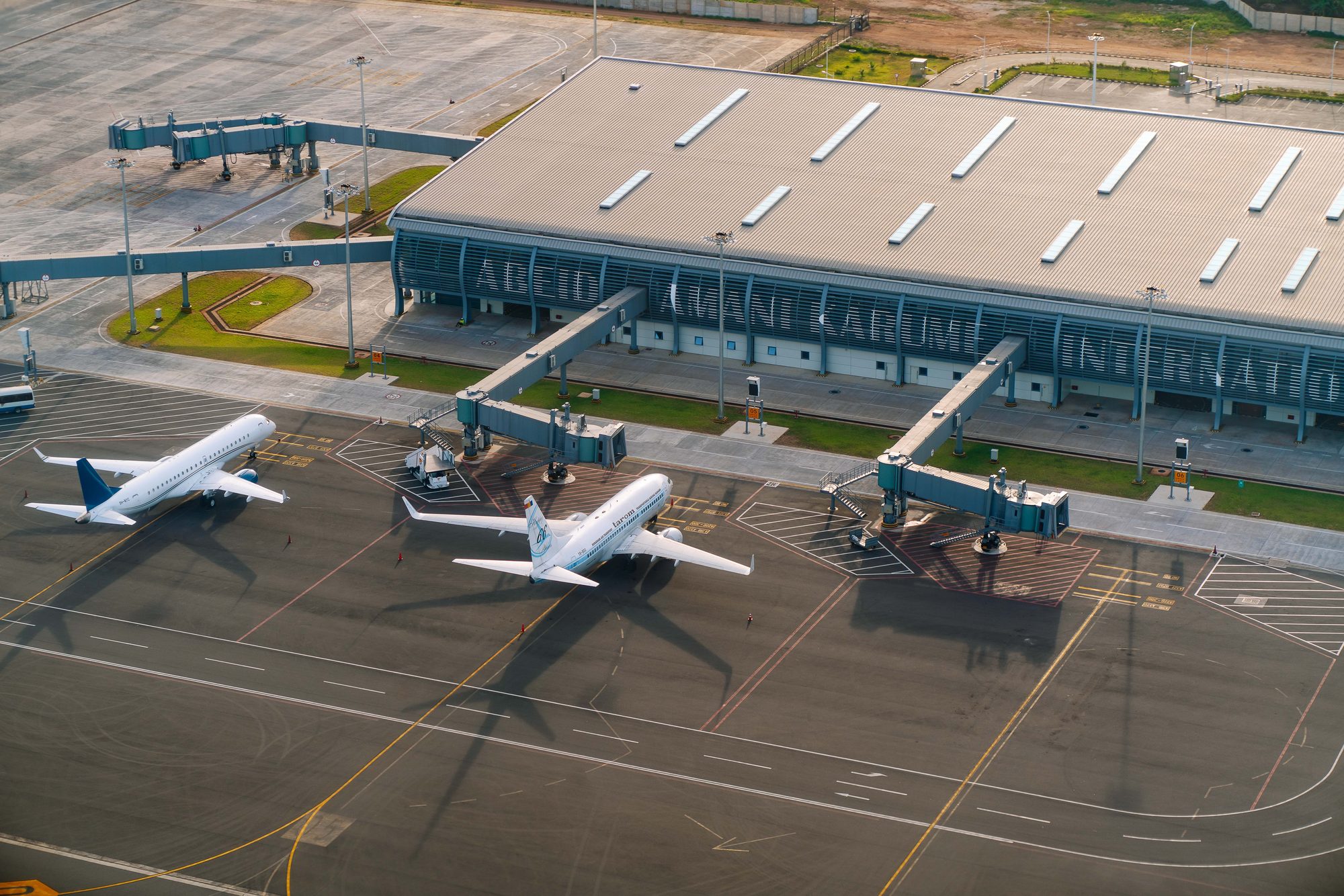 Aerial view of an airport apron with two aircraft parked at the jet bridges