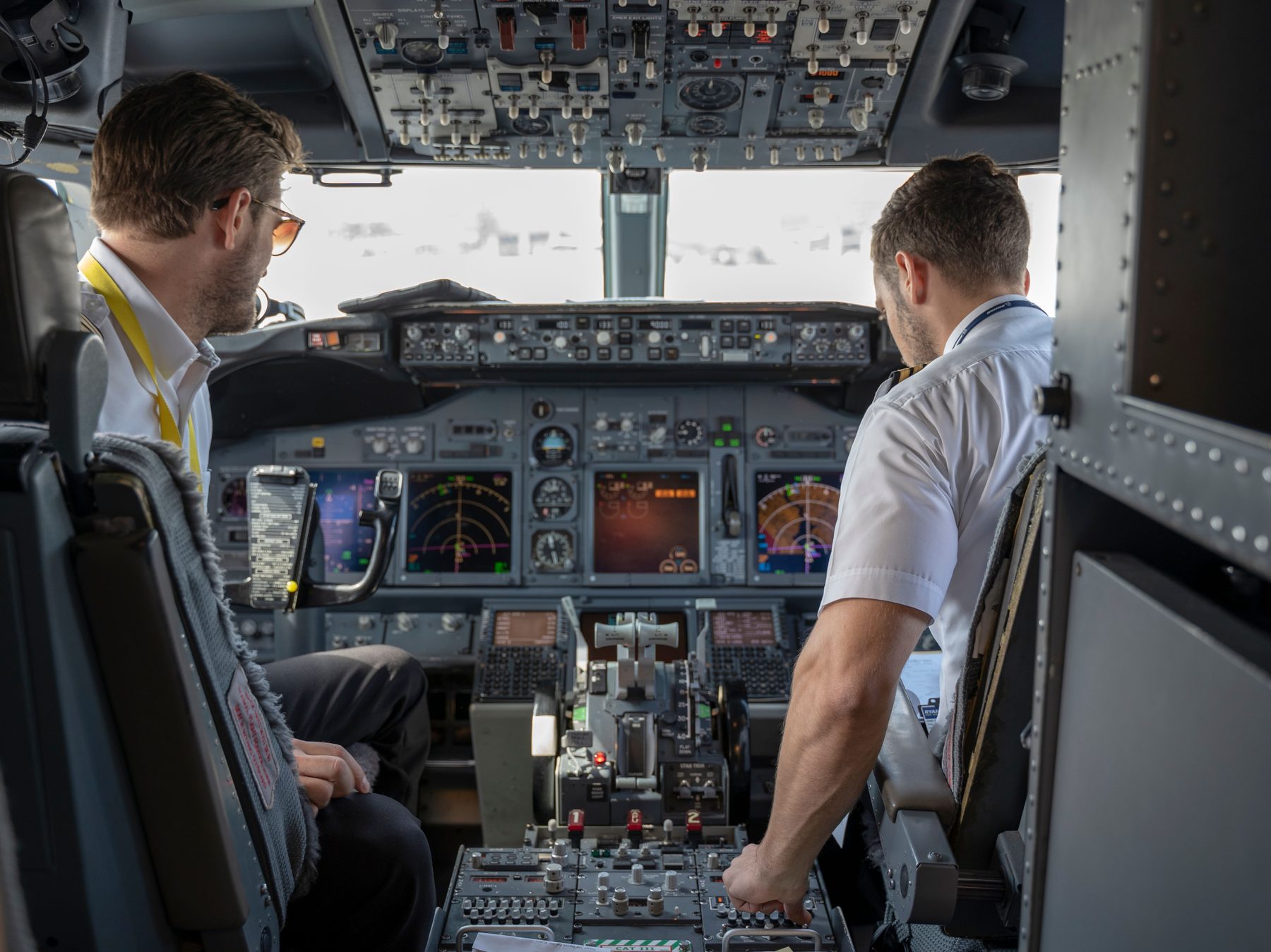 Two pilots in an airliner cockpit during pre-flight checks